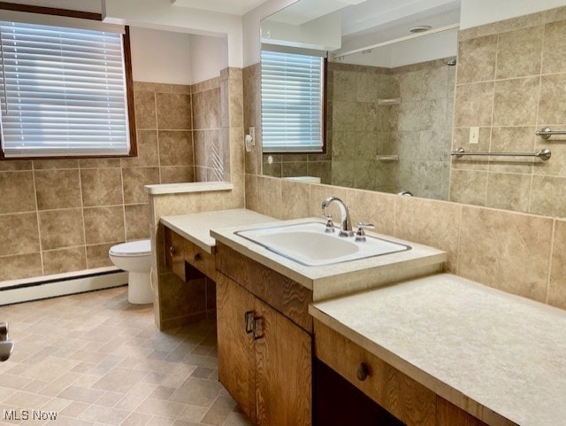 bathroom featuring vanity, a baseboard heating unit, tile walls, and toilet