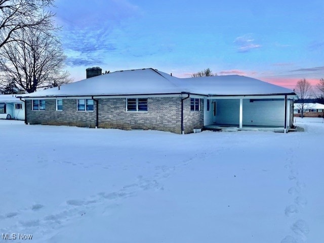 snow covered rear of property featuring a garage