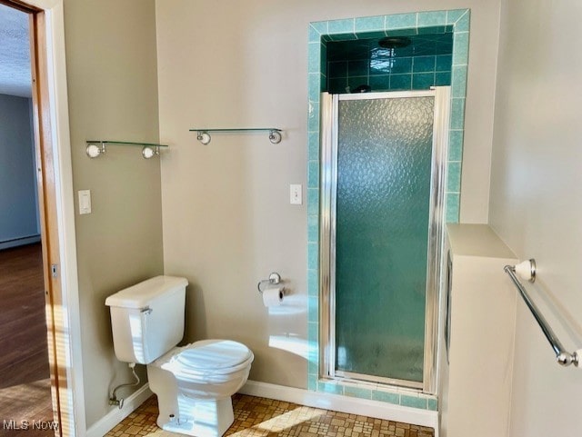 bathroom with baseboard heating, toilet, and walk in shower