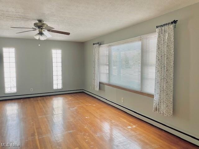 empty room with hardwood / wood-style flooring, ceiling fan, a textured ceiling, and baseboard heating