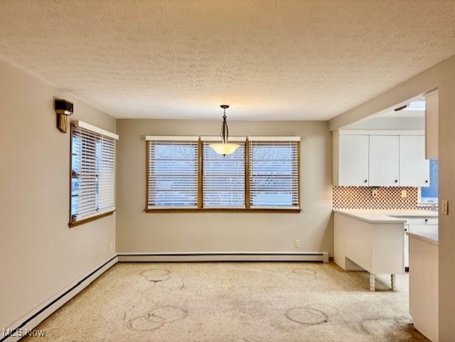 unfurnished dining area featuring a baseboard heating unit, light carpet, and a textured ceiling