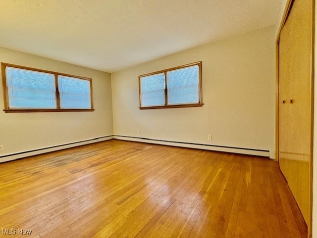 spare room with baseboard heating and light hardwood / wood-style flooring