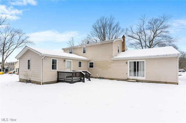 snow covered back of property with a deck