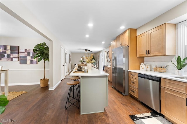 kitchen with dark wood-type flooring, a breakfast bar, stainless steel appliances, tasteful backsplash, and a kitchen island