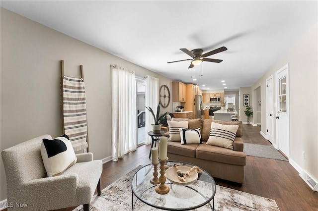 living room featuring dark wood-type flooring and ceiling fan