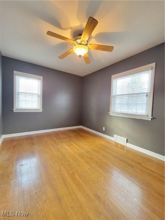 empty room with ceiling fan, light hardwood / wood-style flooring, and a healthy amount of sunlight