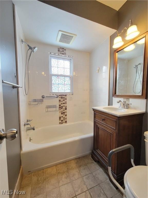 full bathroom featuring tiled shower / bath combo, vanity, and toilet