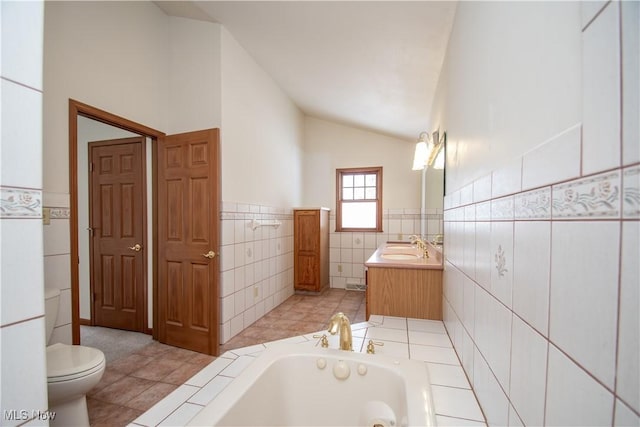 bathroom with lofted ceiling, tile walls, vanity, a tub to relax in, and toilet