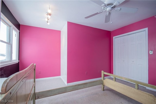 carpeted bedroom featuring ceiling fan, rail lighting, and a closet