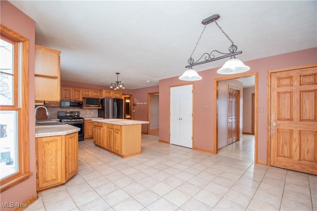 kitchen featuring sink, decorative light fixtures, black appliances, a kitchen island, and backsplash