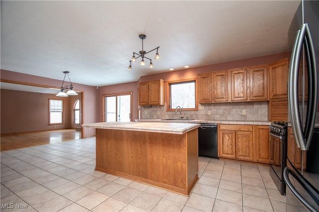 kitchen featuring sink, black appliances, a center island, hanging light fixtures, and backsplash