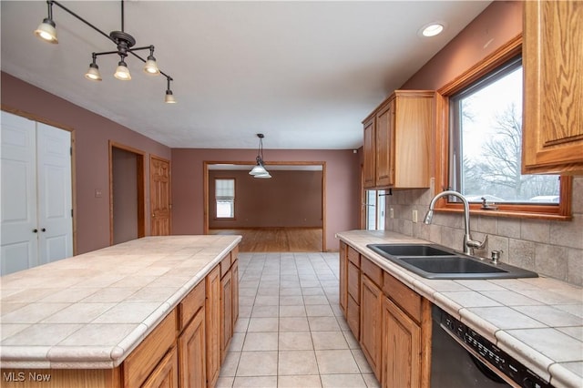 kitchen with pendant lighting, sink, tile countertops, and black dishwasher