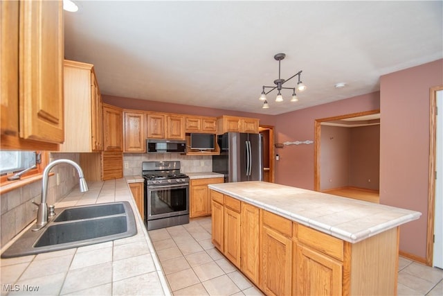 kitchen with sink, appliances with stainless steel finishes, a center island, tasteful backsplash, and tile countertops