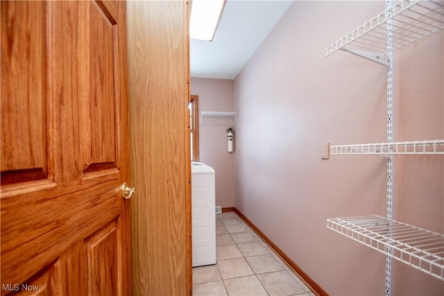 hall featuring washer / dryer and light tile patterned floors