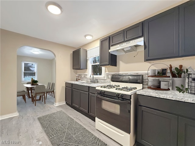 kitchen with white gas range, sink, and light hardwood / wood-style flooring