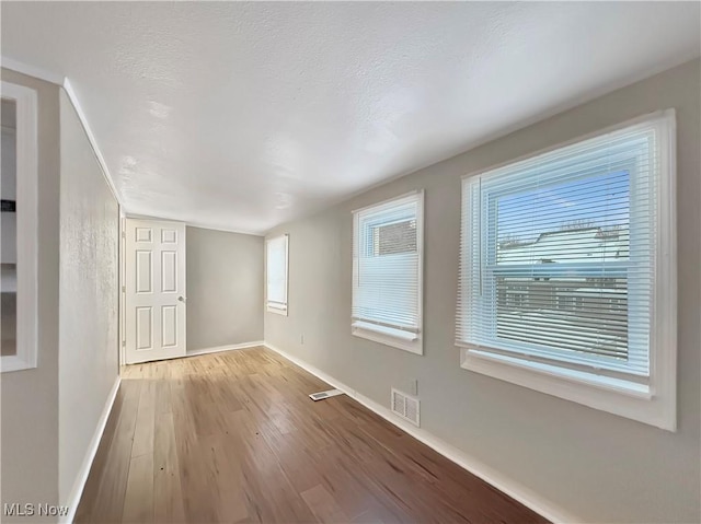 unfurnished room with light hardwood / wood-style floors and a textured ceiling