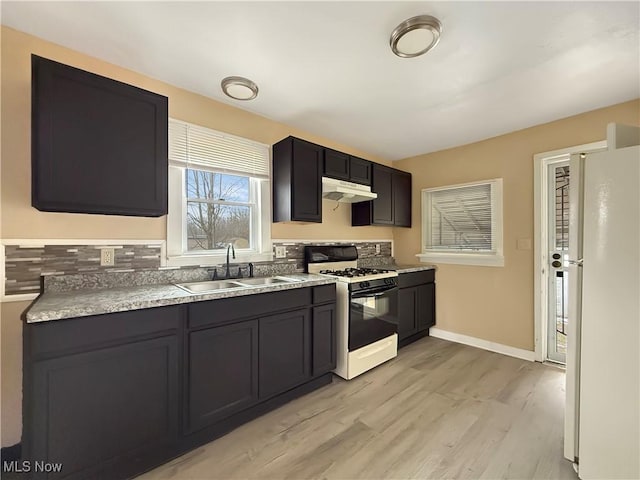 kitchen featuring white refrigerator, range with gas stovetop, sink, and light wood-type flooring