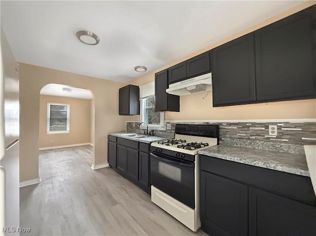 kitchen with sink, backsplash, gas stove, and light wood-type flooring