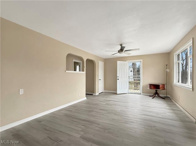 empty room featuring ceiling fan, plenty of natural light, and hardwood / wood-style floors