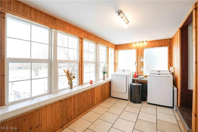 washroom featuring washer and dryer, light tile patterned floors, and wood walls