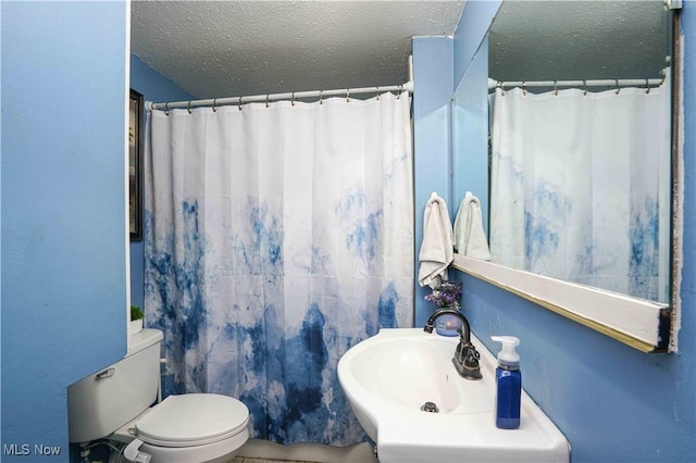 bathroom featuring sink, toilet, a textured ceiling, and walk in shower