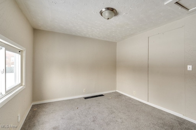 unfurnished room with carpet flooring and a textured ceiling