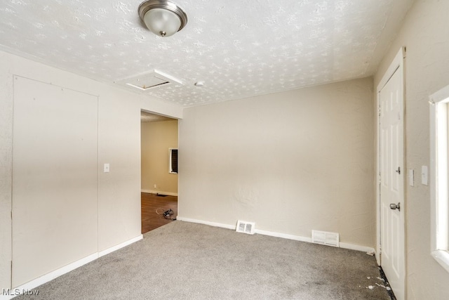 unfurnished room with carpet flooring and a textured ceiling