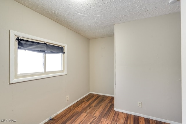 unfurnished room with dark wood-type flooring and a textured ceiling