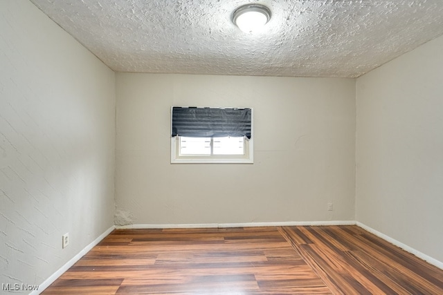 empty room featuring wood-type flooring and a textured ceiling