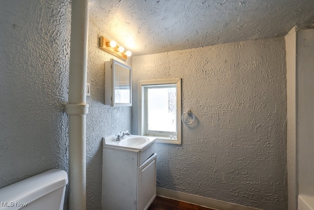 bathroom featuring vanity, toilet, hardwood / wood-style floors, and a textured ceiling