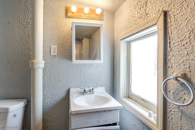 bathroom with vanity, toilet, and a wealth of natural light