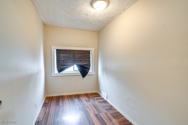 spare room featuring dark wood-type flooring and a textured ceiling