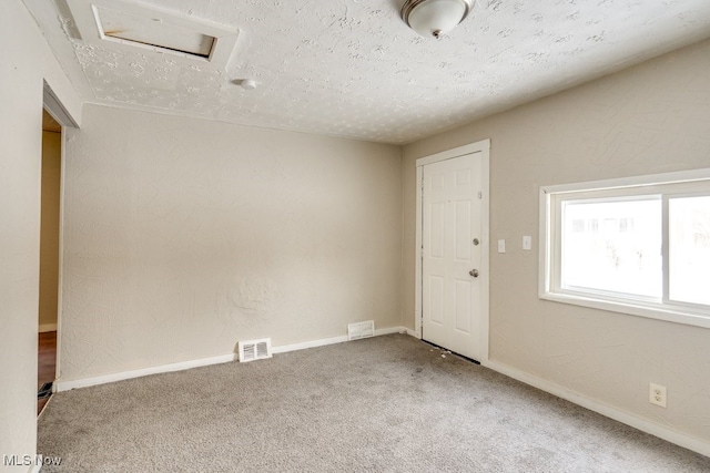 empty room featuring a textured ceiling and carpet flooring