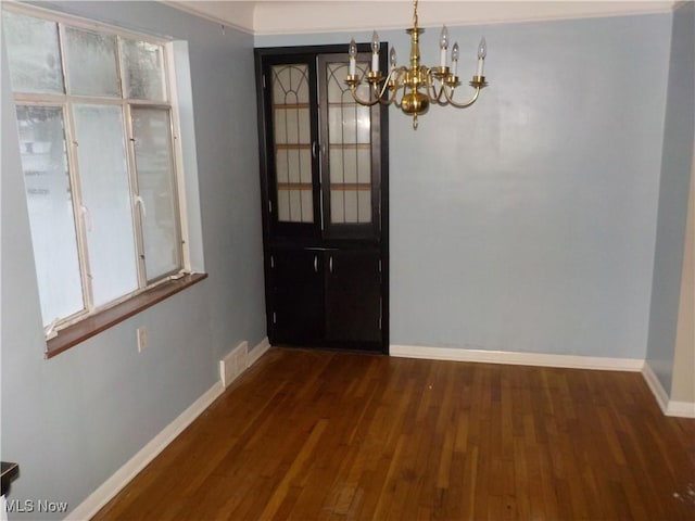 unfurnished dining area with an inviting chandelier and dark wood-type flooring