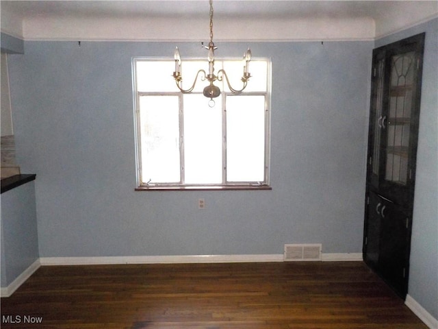 unfurnished dining area with dark hardwood / wood-style flooring, a chandelier, and a wealth of natural light