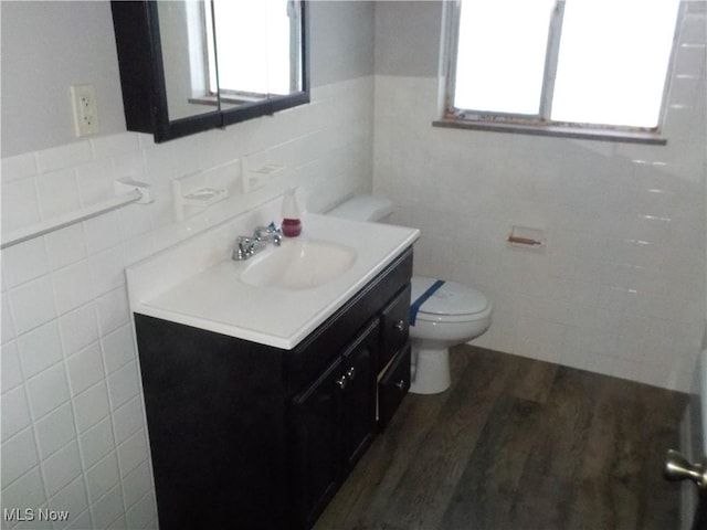 bathroom featuring hardwood / wood-style flooring, vanity, toilet, and tile walls