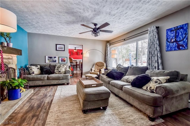 living room with ceiling fan, hardwood / wood-style floors, and a textured ceiling