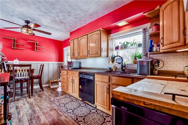 kitchen featuring sink, light hardwood / wood-style flooring, dishwasher, ceiling fan, and tile counters