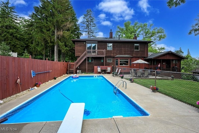 view of swimming pool featuring a patio, a lawn, and a diving board