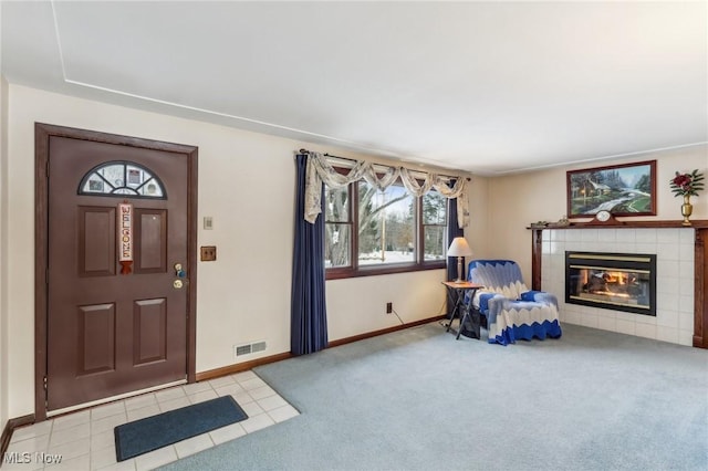 entryway featuring a tile fireplace and light carpet