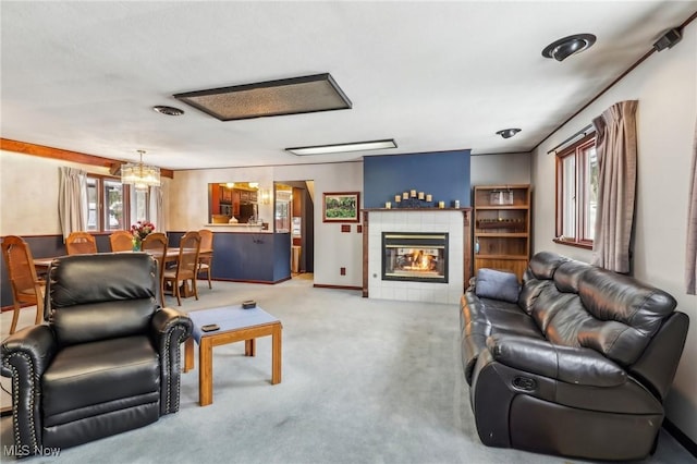 carpeted living room with a tile fireplace and a chandelier