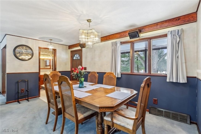 carpeted dining area featuring an inviting chandelier