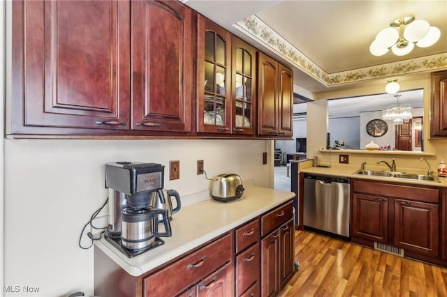 kitchen featuring sink, hanging light fixtures, stainless steel dishwasher, a notable chandelier, and light wood-type flooring