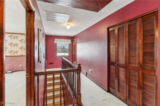 corridor featuring a textured ceiling and carpet