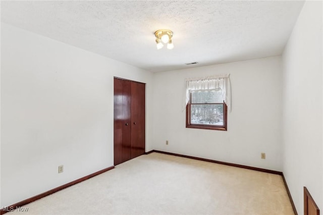 unfurnished room featuring light colored carpet and a textured ceiling