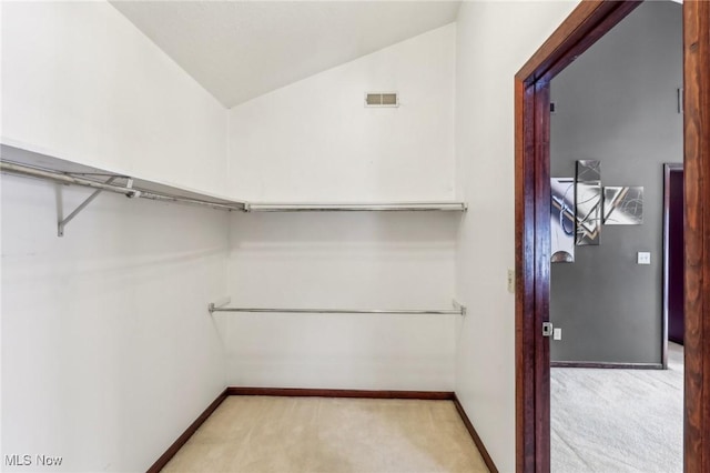 spacious closet featuring vaulted ceiling and light carpet