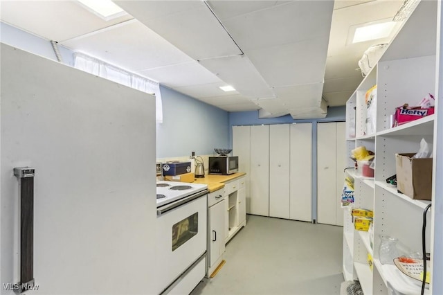 kitchen featuring white cabinetry, fridge, a drop ceiling, and white range with electric cooktop