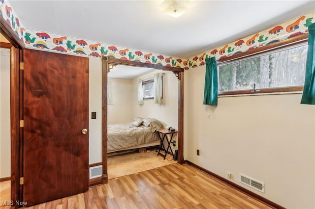 bedroom with light hardwood / wood-style floors and multiple windows