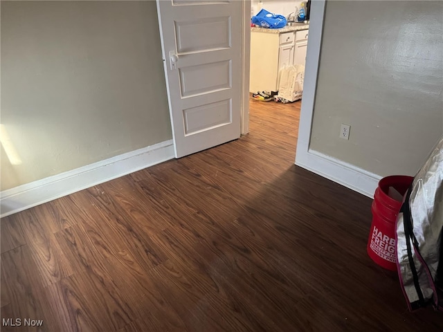 spare room featuring dark wood-style flooring and baseboards