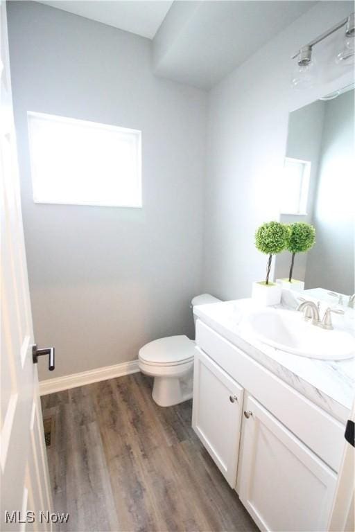 bathroom with toilet, vanity, baseboards, and wood finished floors